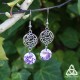 Boucles d'oreilles féeriques aux jolies volutes rondes argentées ornées d'une pierre mauve aux belles facettes violettes.