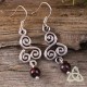 Boucles d'oreilles médiévales ornées de spirales celtiques argentées et d'une perle de Grenat rouge foncé.