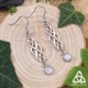Boucles d'oreilles elfiques Odalyne, volutes argentées et Péristérite blanche - vue de face sur fond bois et nature