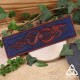 Marque page artisanal en cuir Dragon viking marron et bleu foncé - vue en entier sur fond bois et nature, style médiéval fantasy