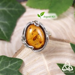Bague elfique Ellea en argent 925 et Ambre véritable, vue de face sur fond bois et feuilles, style médiéval fantasy