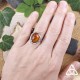 Bague Ellea en argent 925 et Ambre portée au doigt, sur fond nature, mise à l’échelle, style fairycore et automnal