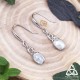 Boucles d’oreilles féeriques Lúmena en argent 925 posées sur fond bois, vues en entier avec crochets d’oreilles, style elfique